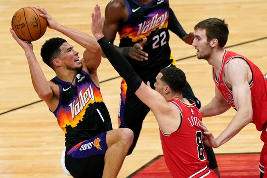 Phoenix Suns guard Devin Booker, left, drives to the basket against Chicago Bulls guard Zach LaVine, center, and forward Luke Kornet during the first half of an NBA basketball game in Chicago, Friday, Feb. 26, 2021. (AP Photo/Nam Y. Huh).