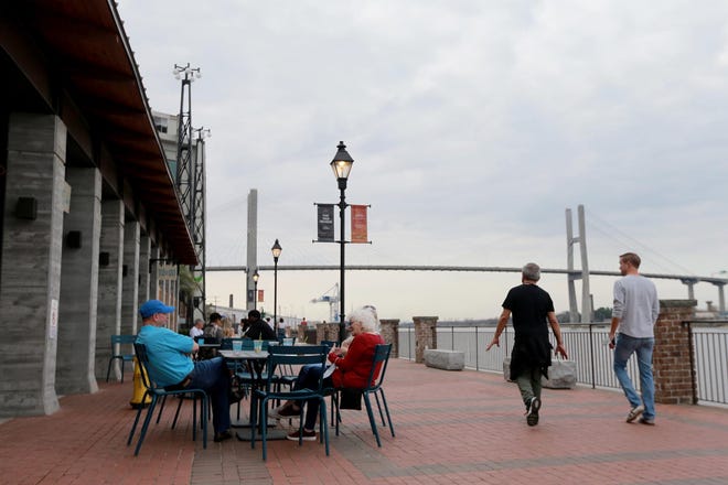 Visitors enjoy drinks and conversation along the riverwalk at the Plant Riverside District.