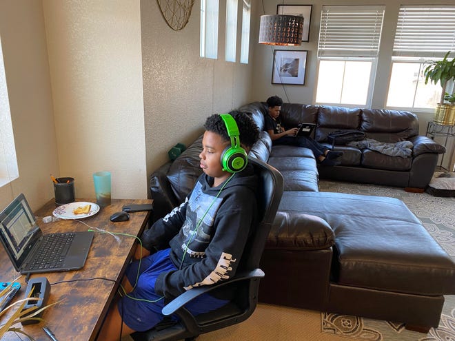 Maddox Egart, 13, concentrates on schoolwork as his brother, Kane, 14, writes an essay behind him in their Denver home on Tuesday, Feb. 23, 2021.