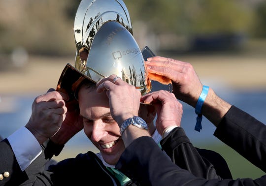 Kevin Sutherland gets help donning his trophy after coming from behind in the final round of the Cologuard Classic at the Omni Tucson National Resort, Tucson, Ariz., Sunday, Feb. 28, 2021.