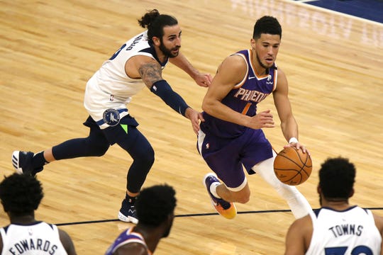 Phoenix Suns' Devin Booker (1) drives the ball past Minnesota Timberwolves' Ricky Rubio (9) in the first half of an NBA basketball game, Sunday, Feb. 28, 2021, in Minneapolis. (AP Photo/Stacy Bengs).