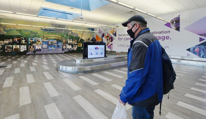 Adam McGaughey leaves Erie International Airport after arriving on a flight in February. Portraits of the Northwestern Pennsylvania Aviation Hall of Fame members can be seen at back left.