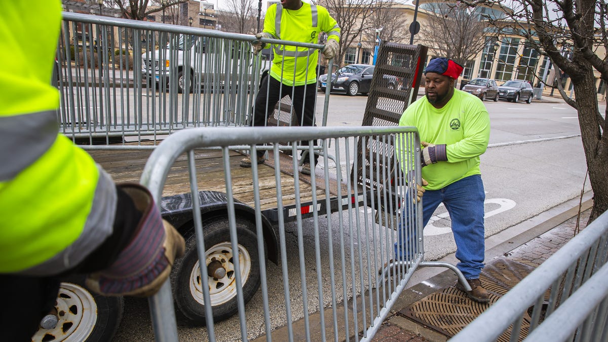 Aaron Pearl, with Springfield Public Works, helps load fencing back onto a trailer along Jefferson Street as crews pickup the preparations that had been put in place for the St. Patrick's Day parade after it was postponed because of the COVID-19 pandemic, Thursday, March 12, 2020, in Springfield, Ill. The 2021 parade also has been postponed because of pandemic concerns with large gatherings. [Justin L. Fowler/The State Journal-Register]