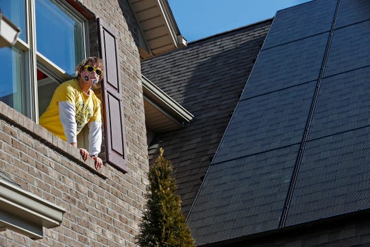 Joey Miles hangs out the second floor window by some of the solar panels on his home Wednesday, March 3, 2021 in the Franklin Trace neighborhood in Indianapolis. He faced obstacles from his HOA to get solar power on his home. Now he has them, but they are not optimally oriented because they have to be on the side of the house away from street view.