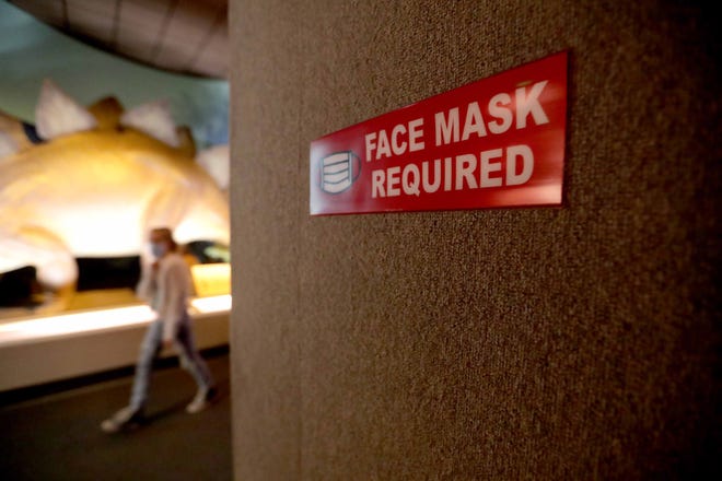 A "face mask required" sign hangs on the wall at the Milwaukee Public Museum.
