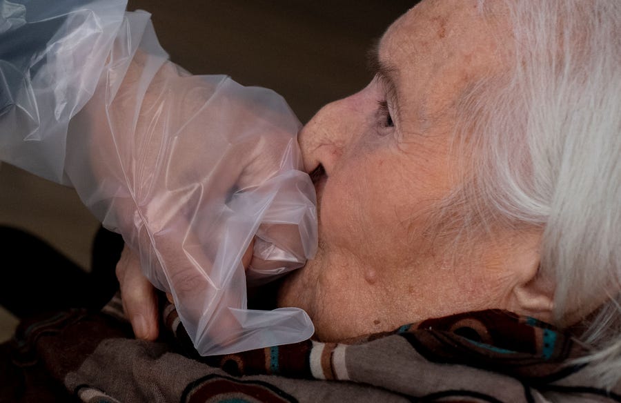 A resident of the Villa Sacra Famiglia nursing home in Rome kisses the hand of her grandson through a plastic screen in a "Hug Room" on March 3 amid the COVID-19 pandemic.