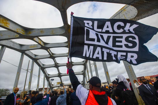 A Black Lives Matter demonstrator waves a flag on the Edmund Pettus Bridge Sunday, March 3, 2019, during the Bloody Sunday commemoration in Selma, Ala.