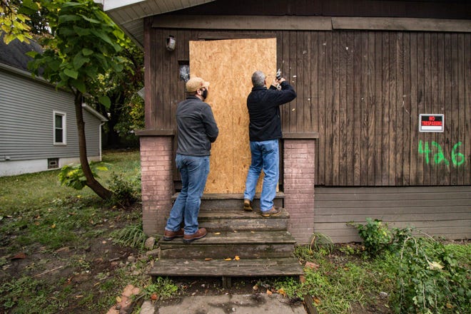 Summit County Land Bank Program Director Jim Davis and staff attorney Drew Reilly secure plywood over the front door at 426 McGowan St. in Akron's Middlebury neighborhood.