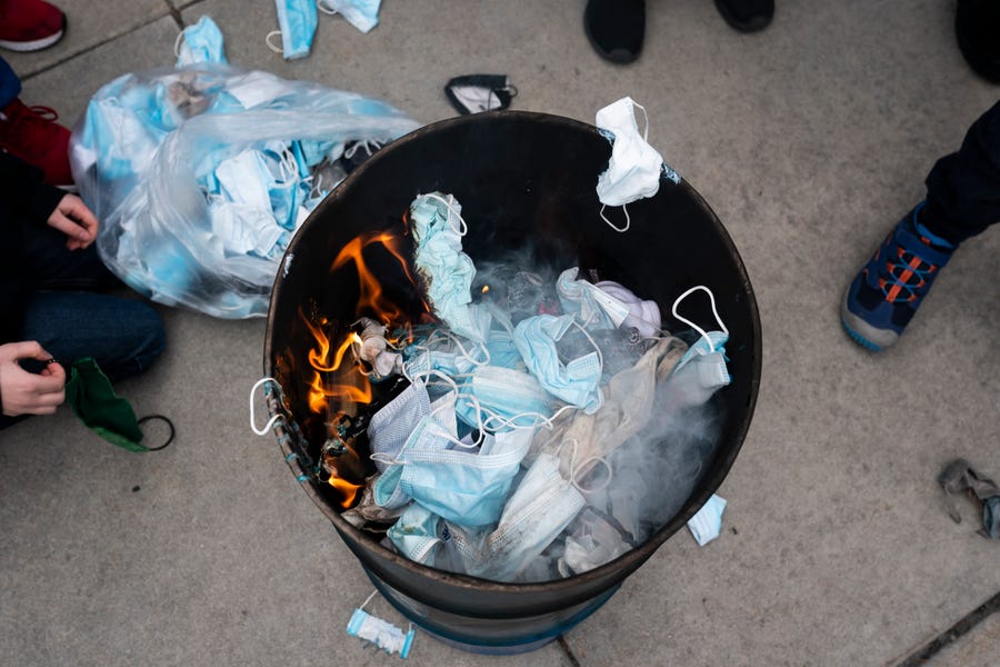 Attendees toss surgical masks into a fire during a mask burning event at the Idaho Statehouse on March 6, 2021 in Boise, Idaho.