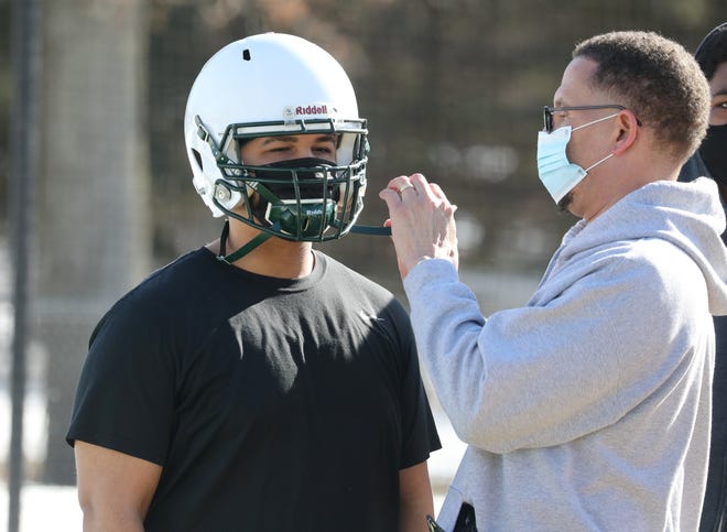 Ramapo football coach Kevin Bullock helps Raj Balkishun fit his helmet over a mask during the first day of practice at the school March 8, 2021.