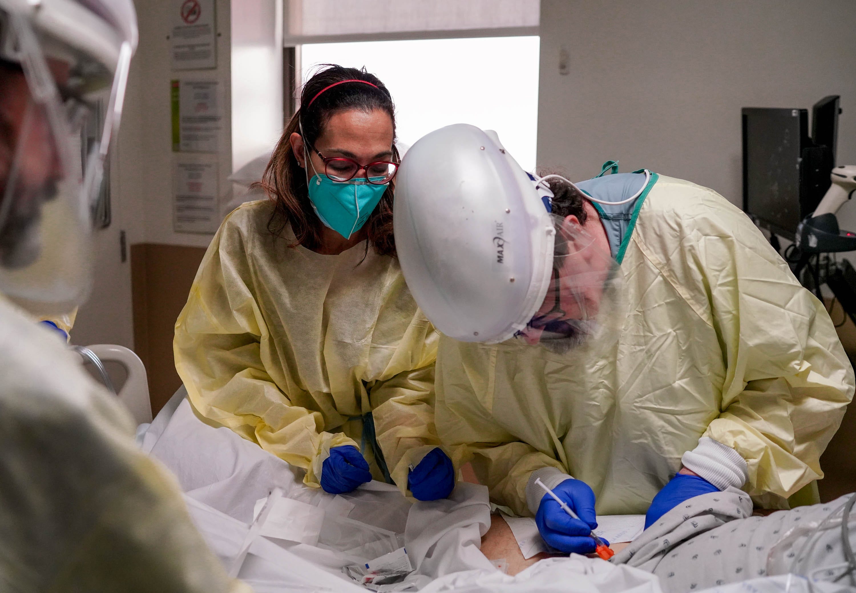 Dr.  Marwa Kilani, left, a hospice and palliative care specialist, watches a colleague administer medication to an IV patient of COVID-19 at the Providence Holy Cross Medical Center in Los Angeles on Wednesday, February 10, 2021.