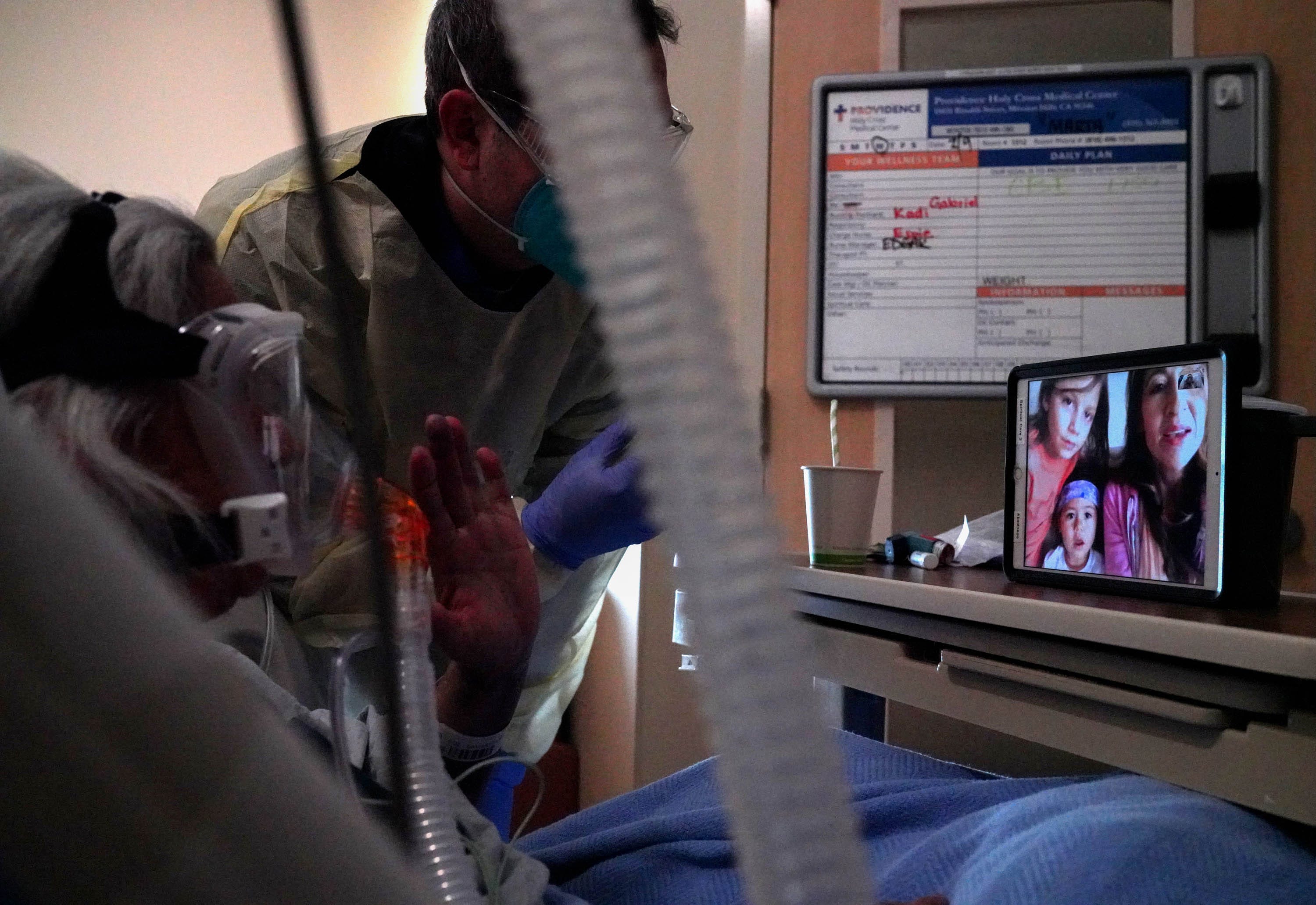 Chaplain Kevin Deegan facilitates a call between Marta Aguilar, a COVID-19 patient at Providence Holy Cross Medical Center, and Cheyenne Quintanar, her daughter-in-law, on Friday, Feb. 12, 2021, at Providence Holy Cross Medical Center in Mission Hills, Calif.