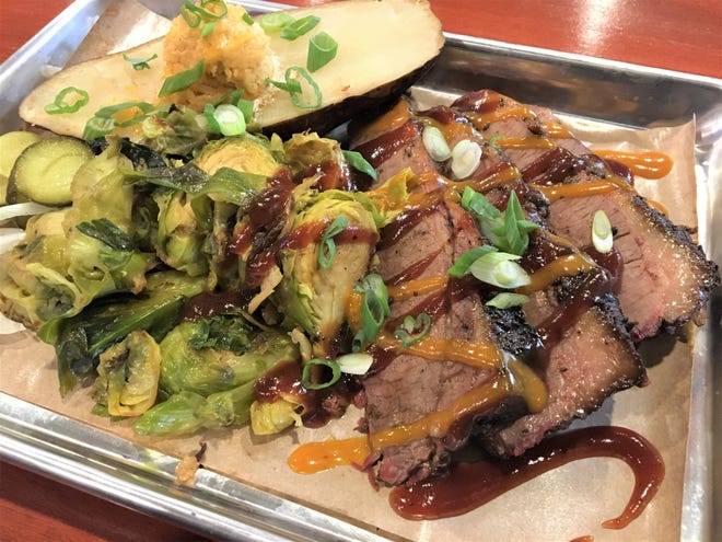 The signature dish at One Nation Tap & Table is the Smoked Brisket, cooked in the One Nation Smoker, with two house-made sauces, a smoked baked potato with sriracha honey butter and roasted brussel sprouts.