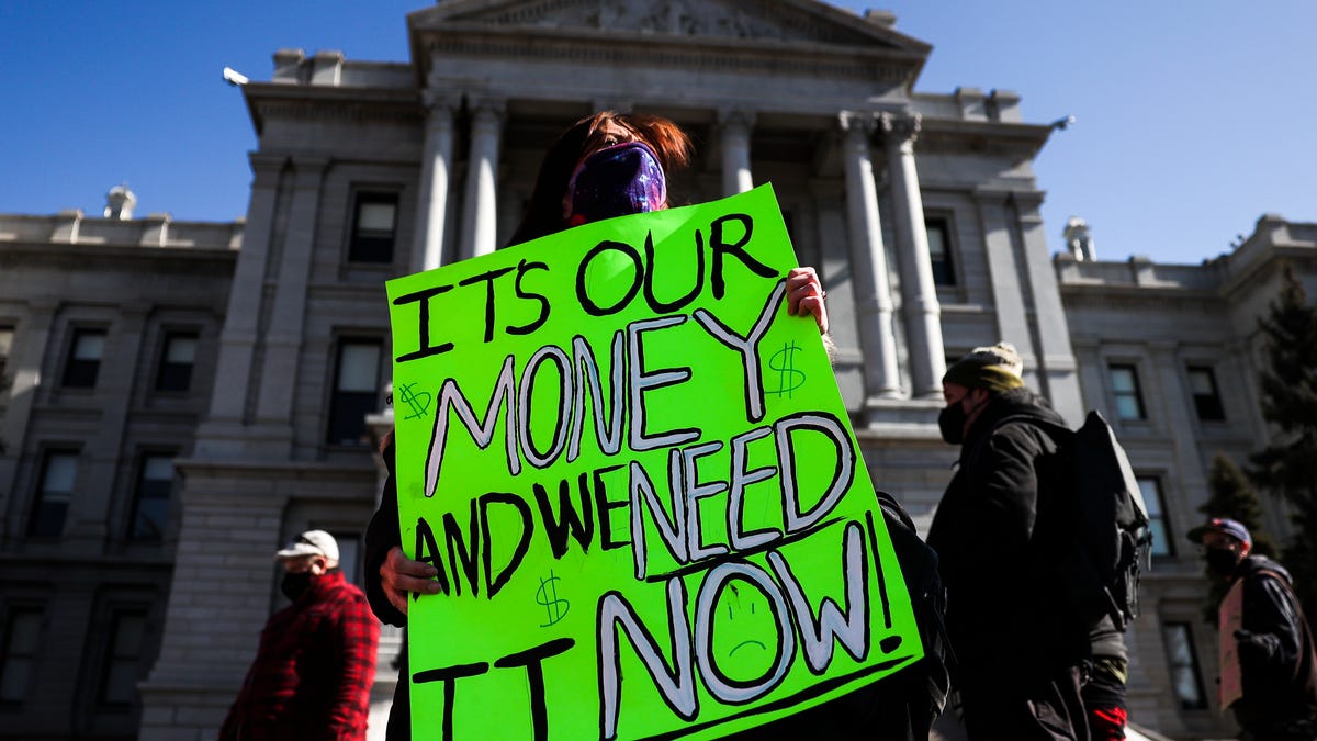 Monica Walsh holds a sign outside the Colorado State Capitol during a demonstration demanding answers about a lack of financial relief from the state on February 8, 2021 in Denver, Colorado.