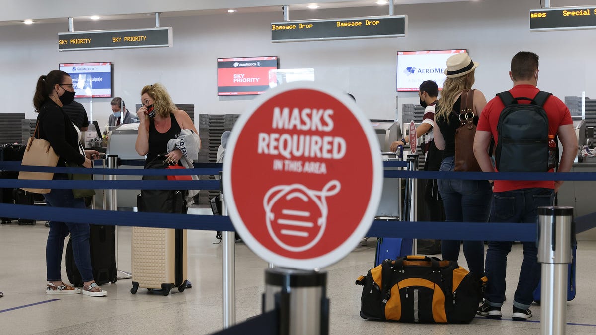 A sign reading, 'masks required in this area,' is seen as travelers prepare to check-in for their Delta Airlines flight at the Miami International Airport on February 01, 2021 in Miami, Florida.