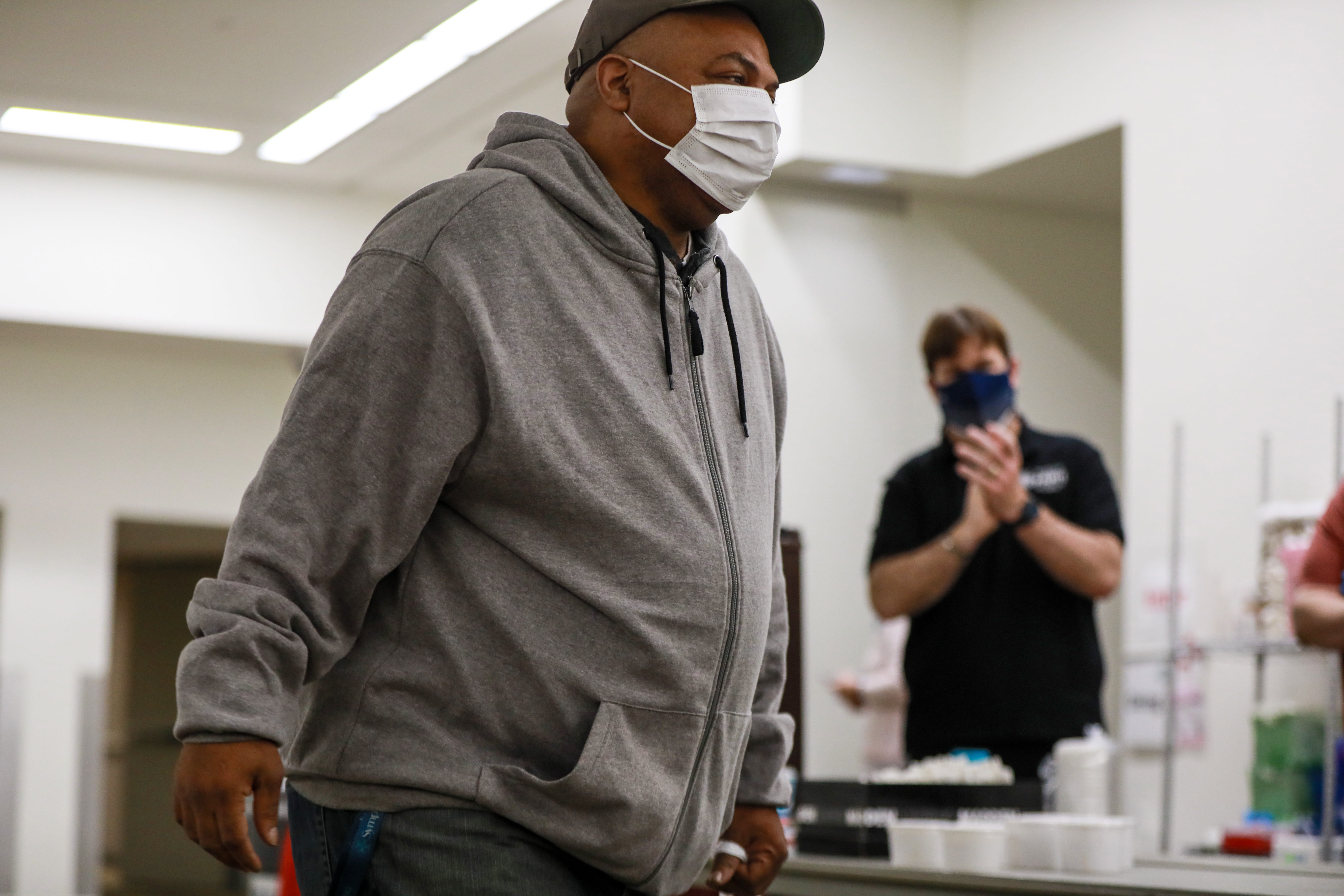 William Randle, 55, of Detroit sings the Oscar Meyer Weiner song while receiving breakfast at the Pope Francis Center at the TCF center in Detroit on Saturday, March 6, 2021. In the background Ford Motor Co. CEO Jim Farley applauds him.