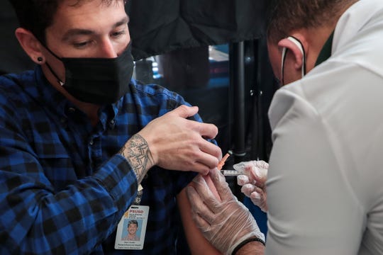 Sean Snider, paraprofessional educator at Cabot Yerxa Elementary School in Desert Hot Springs, Calif., receives a Johnson & Johnson COVID-19 vaccine from Rite Aid pharmacy manger Louie Gironella at a Palm Springs Unified School District vaccine clinic on Wednesday, March 10, 2021.