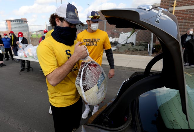 (Left) Tyler Garrett, 21 and a Schoolcraft College baseball player loads another car with frozen turkeys at The Corner Ballpark at Michigan and Trumbull in Detroit on Thursday, March 11, 2021.Meijer donated 1,000 turkeys to help families in need through a partnership with Detroit Police Athletic League (PAL).  The giveaway is one of several that will encompass more than $1 million (50,000 turkeys) of food relief for local food banks across the Midwest. 