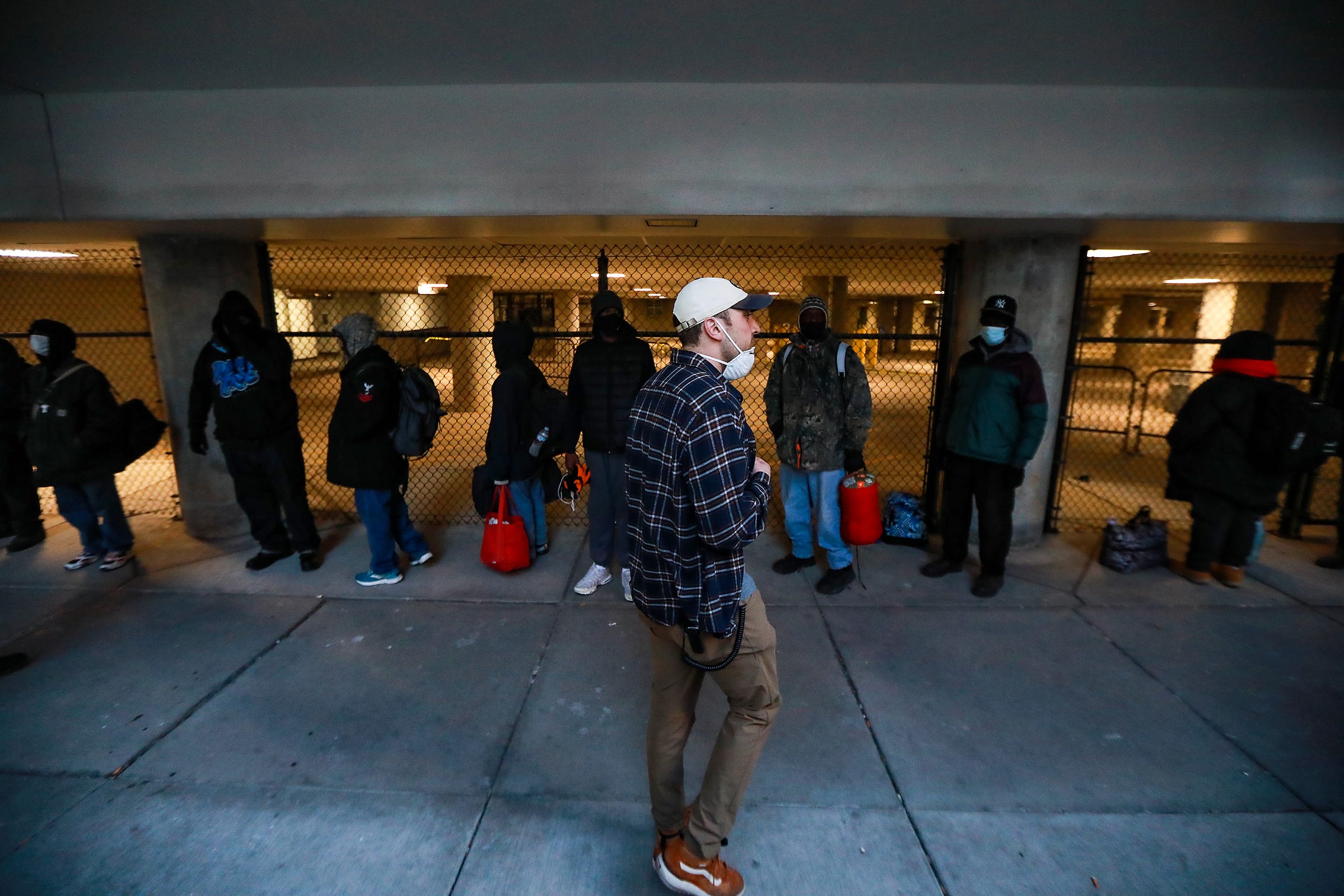 Program Director Harrison Plaskey, 28, of Detroit, greets men and women waiting in line outside of the TCF Center before entering the Pope Francis Center to receive breakfast and vital resources in downtown Detroit on March 6, 2021.