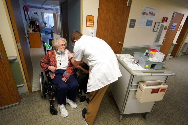 FILE - In this Jan. 8, 2021, file photo, Jean Allen, 96, left, receives the first shot of the Pfizer vaccination for COVID-19, from a Walgreens Pharmacist, right, at Queen Anne Healthcare, a skilled nursing and rehabilitation facility in Seattle. Allen survived catching COVID-19 before she was vaccinated, during a 2020 outbreak of COVID-19 that killed more than a dozen residents and two staff members. (AP Photo/Ted S. Warren, File)