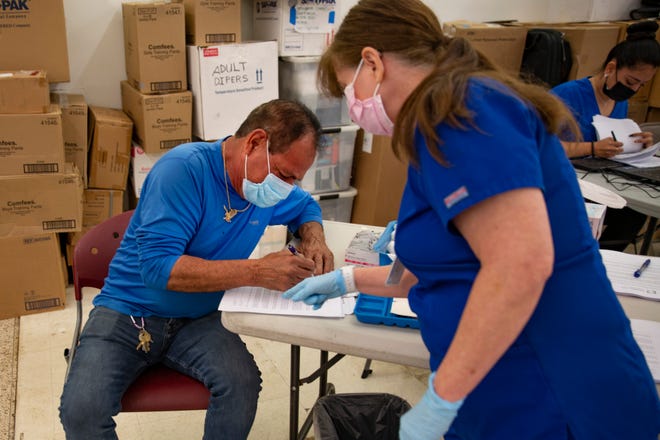 Armando Izaguirre, of Immokalee, fills in paper work before receiving his COVID-19 vaccine during a Healthcare Network vaccination clinic, Tuesday, Feb. 9, 2021, in Immokalee.