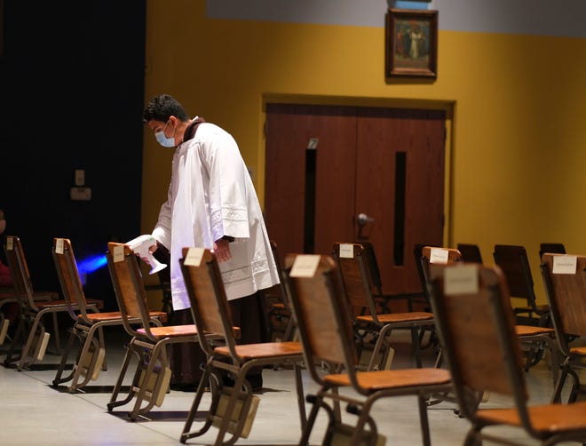 Giovani Rangel sprays a chair with sanitizer after Mass  at Little Flower Catholic Church in south Oklahoma City.