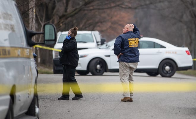 A homicide investigator rubs his head as he surveys the scene around a home on the 330 block of North Randolph Street in Indianapolis on Sunday, March 14, 2021, after four people, including a child, were found dead inside a home Saturday.