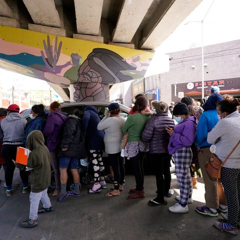 People surround a car as it arrives carrying food 