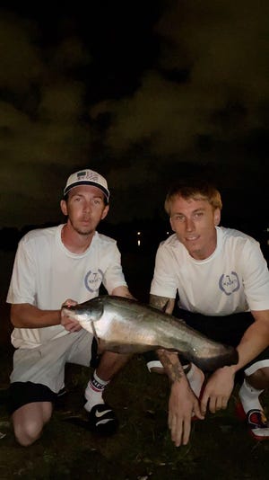 Fishing Lake Ida at night, Travis Massey (left) and Cody Turer, both of Lake Worth, caught multiple clown knifefish on live shad including this rare spotless individual.