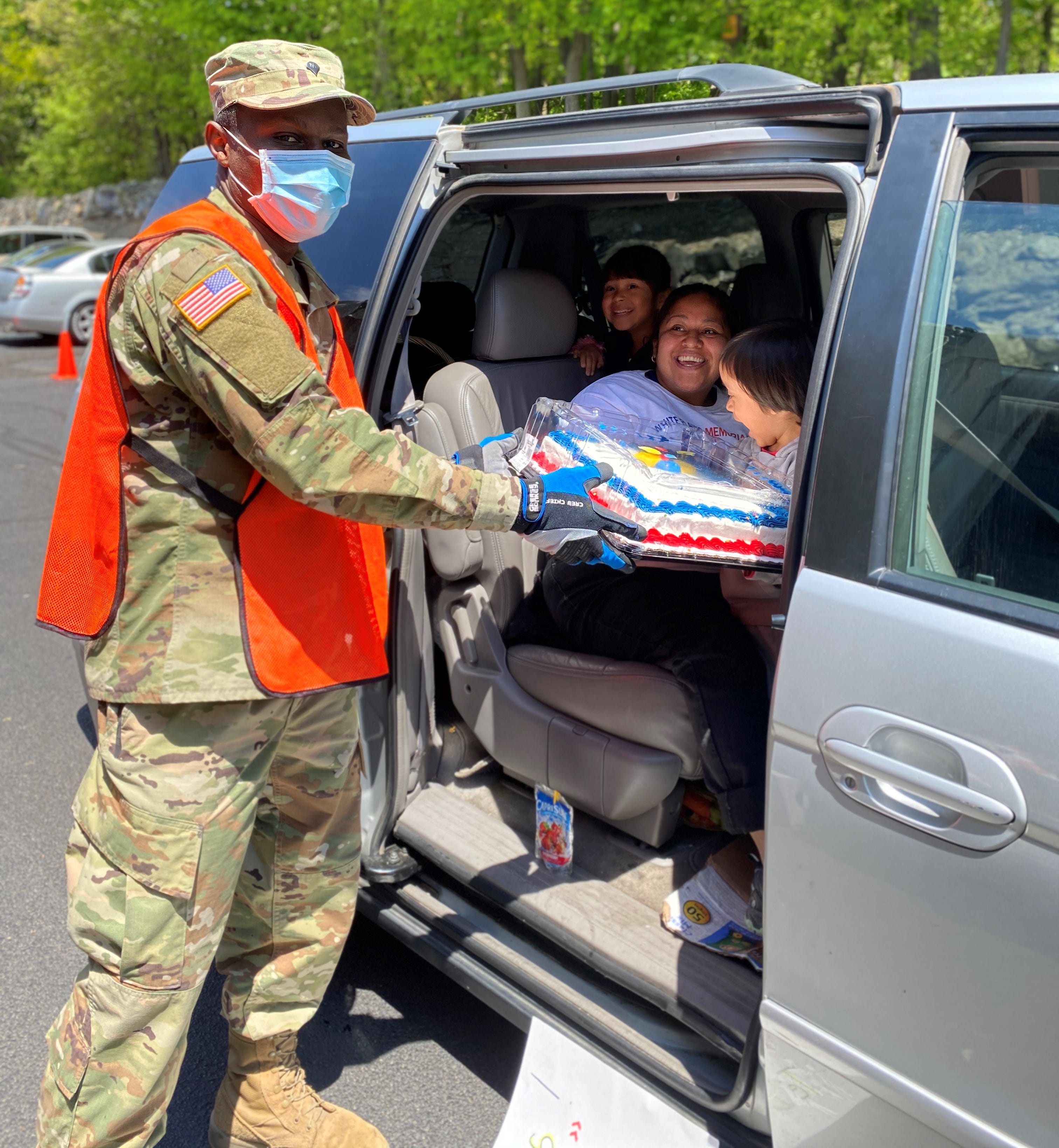 National Guard Specialist David Conteh gives a cake to a surprised birthday boy whose family drove up to Feeding Westchester's weekly food distribution at its Elmsford warehouse.