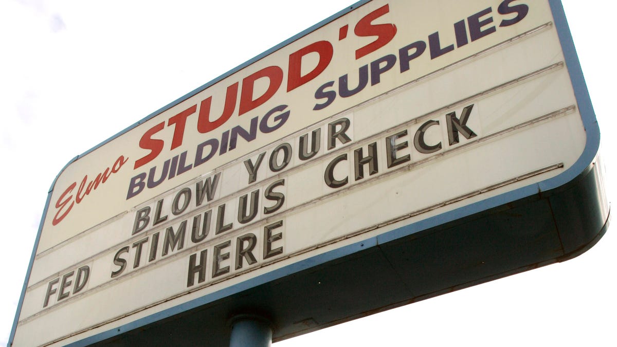 Lumber is unloaded under a marquee sign urging people to spend their tax rebates at a building supplies store in Tigard, Ore., Monday, May 5, 2008.