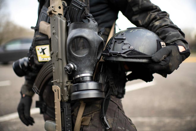 A member of the Boogaloo Boys armed with an assault rifle, gas mask and combat helmet stands outside of the Oregon State Capitol  in Salem, during a nationwide protest called by anti-government and far-right groups supporting President Donald Trump and his claim of electoral fraud in the 2020 election.