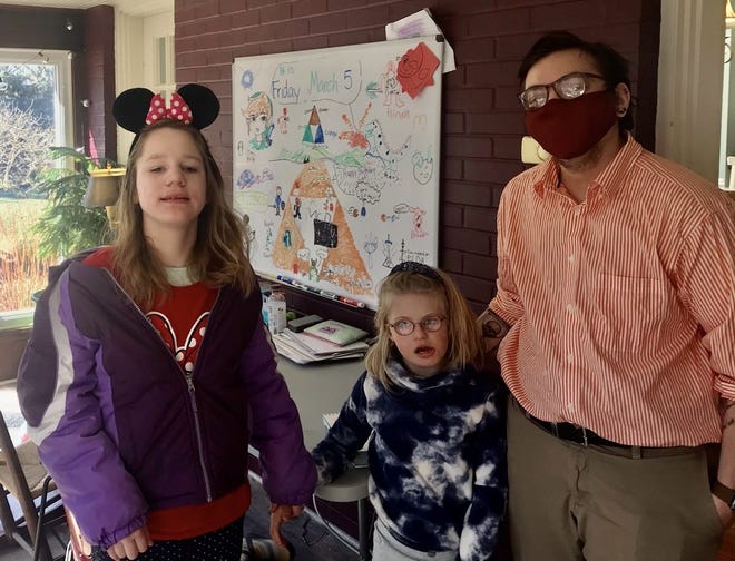 Jocelyn Burkholder, 10, and Lyra Christensen, 8, stand with their educational pod teacher, Declan McCaslin.