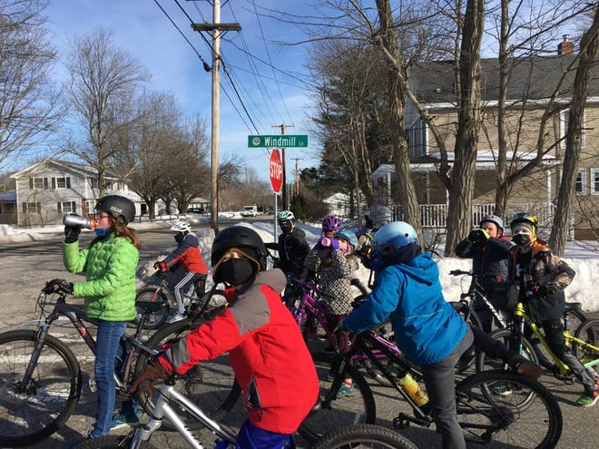 Second and third graders with a fifth grade junior coach, in green, take a water break after riding up the long Windmill Road climb in Hampton.