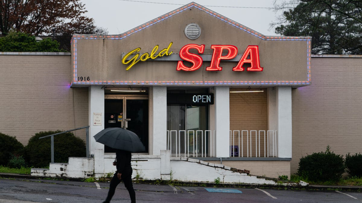 A man walks past a massage parlor where three women were shot and killed on March 17, 202,1 in Atlanta, Georgia. Suspect Robert Aaron Long, 21, was arrested after a series of shootings at three Atlanta-area spas left eight people dead on Tuesday night, including six Asian women. Long, who is now in custody, reportedly made reference to a "sex addiction" in conversations with investigators.