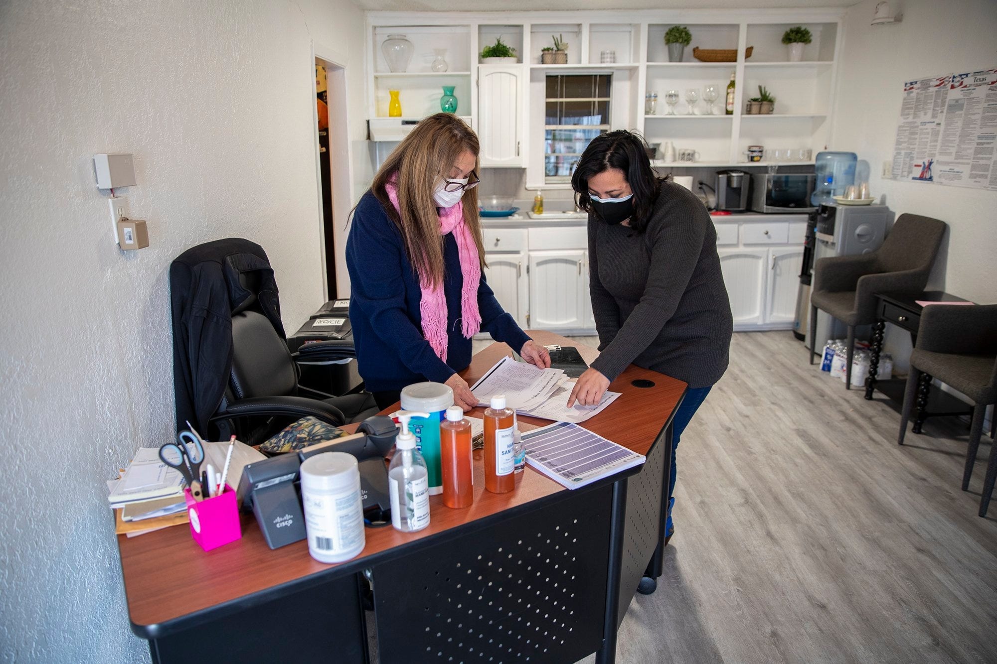 Jill Ramirez, left, and Ma Isabel Lopez, right, look over sign-up sheets from a list of people that they will help register to take the COVID-19 vaccine at the Latino Healthcare Forum office in East Austin on Monday, March 1, 2021. Most of the people who signed up are unable to get online themselves.