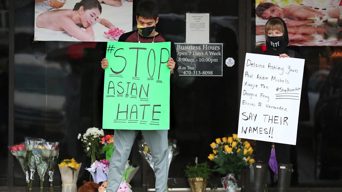 After dropping off flowers Jesus Estrella, left, and Shelby stand in support of the Asian and Hispanic community outside Young's Asian Massage Wednesday, March 17, 2021, in Acworth, Ga. Asian Americans, already worn down by a year of racist attacks fueled by the pandemic, are reeling but trying to find a path forward in the wake of the horrific shootings at three Atlanta-area massage businesses that left eight people dead, most of   them Asian women. 