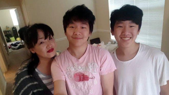 Hyun Jung Grant stands with her sons, Randy Park, center, and Eric Park, in this undated family photo.