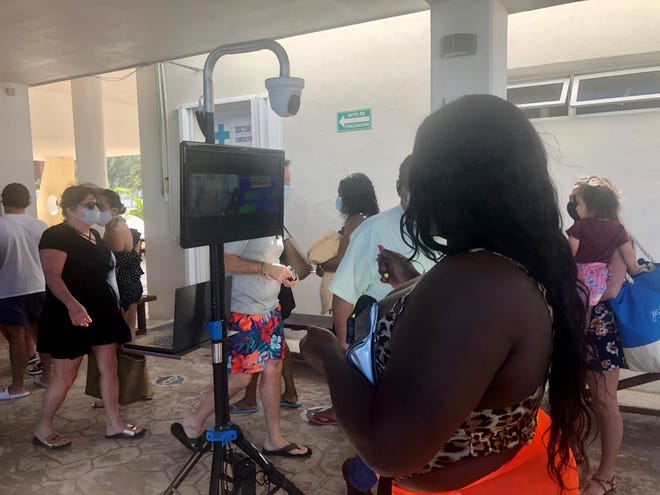 Travelers boarding a sunset cruise to Isla Mujeres in Mexico go through a thermal temperature screening before boarding.
