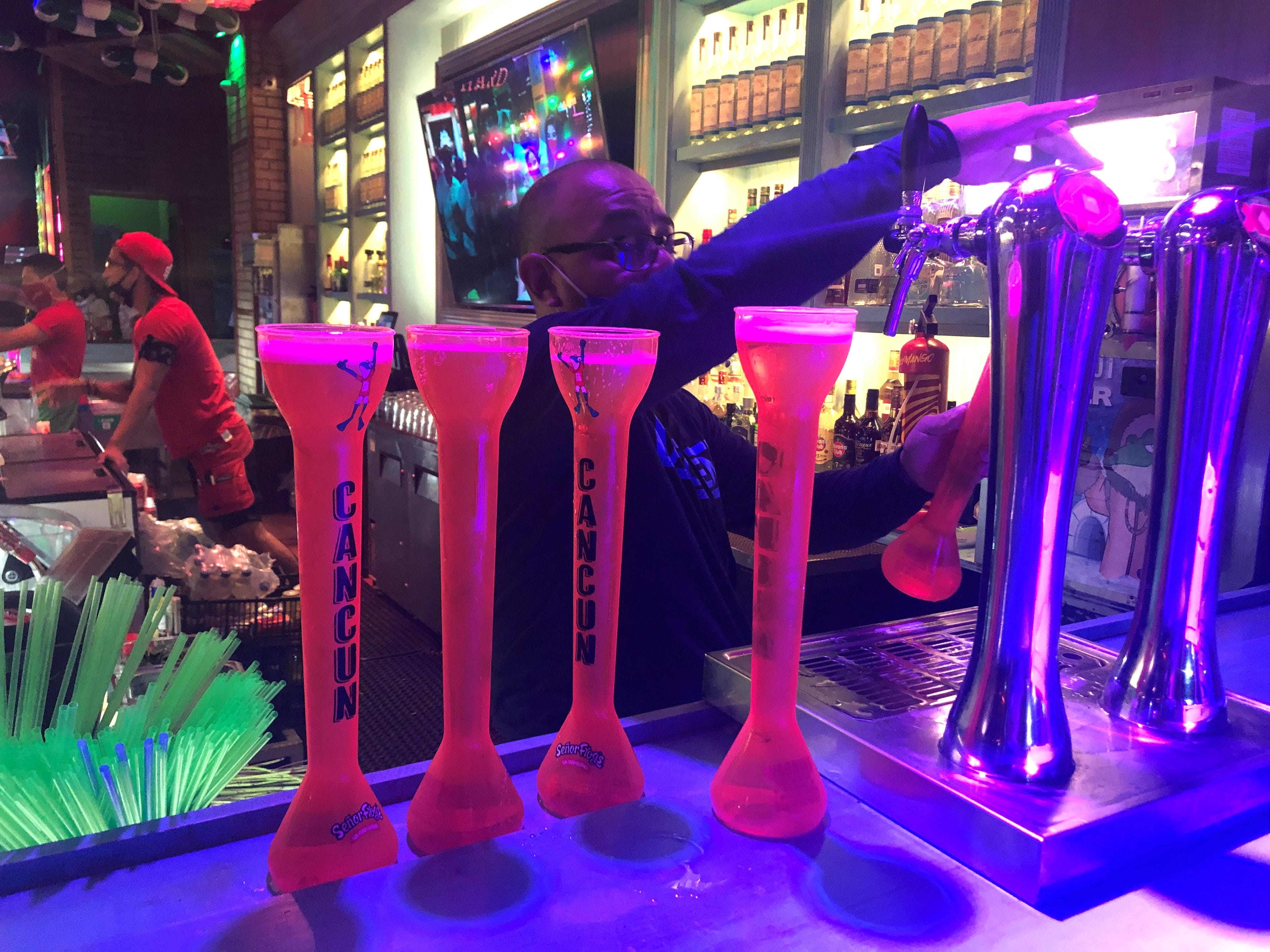 A bartender at Senor Frog's, a popular tourist spot in downtown Cancun, serves Dos Equis in 28-ounce souvenir cups.