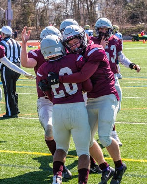 Bishop Stang teammates embrace Carlo Acosta after his touchdown to tie up the score in the second quarter against Archbishop Williams.