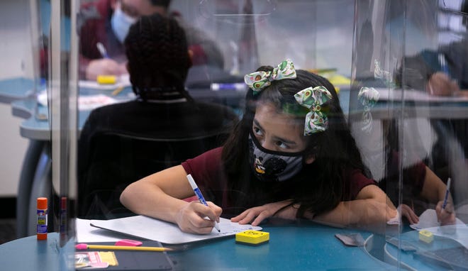 Behind clear partitions for COVID-19 concerns, Yajaira Denisse Carmona Rojas, 11, does social studies work at Gateway Elementary School in Phoenix on March 18, 2021. Other than a brief return to in-person school in the fall, this was the first day the sixth graders were back in-person at the school since the COVID-19 pandemic began in March 2020.