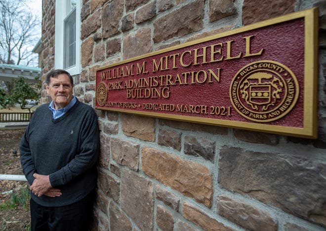 William Mitchell, of New Britian, stands next to a plaque renaming the Park Administration Building in Middletown in his name, as he is retiring as executive director of Bucks County Parks and Recreation.