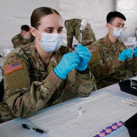 Army health specialists fill syringes with Pfizer'