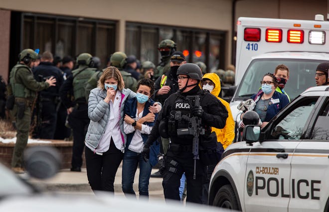 Health care workers walk out of a King Soopers Grocery store after a gunman opened fire on March 22, 2021, in Boulder, Colorado.