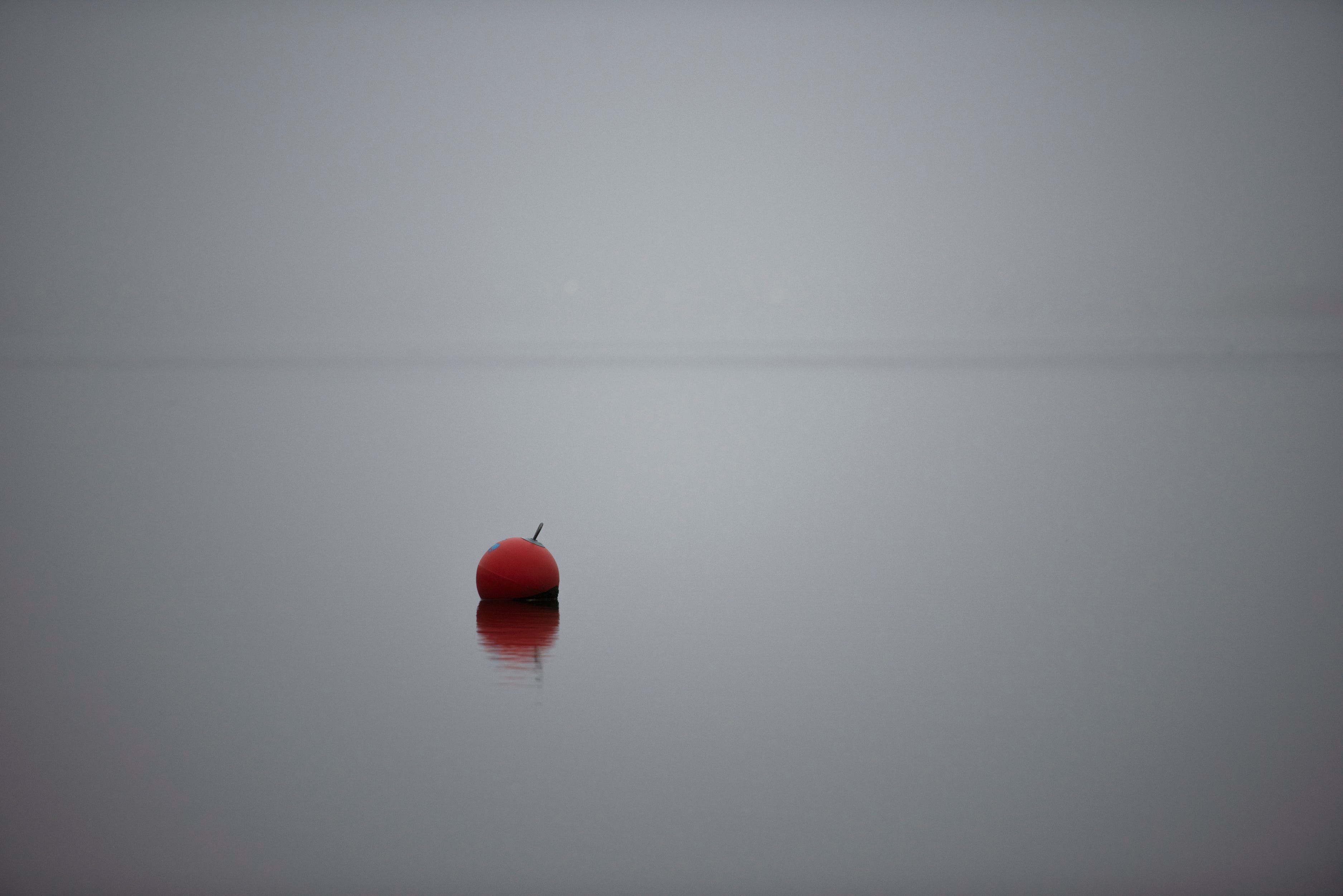 A buoy sits on the Hackensack River as fog rises around it.