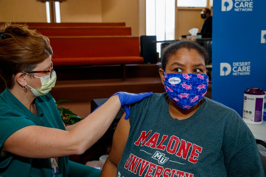 Felicia Wash, 49, of Palm Springs receives the Pfizer COVID-19 vaccine from Desert Care Network registered nurse Sherry Elliott at Ajalon Baptist Church in Palm Springs, Calif., on March 23, 2021. Wash, a member of the church, also volunteered at the vaccine clinic. 