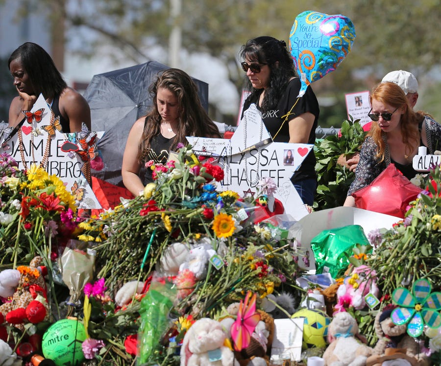 Mourners bring flowers to a memorial for  victims of a shooting at Marjory Stoneman Douglas High School in Parkland, Fla. Seventeen students and staff were killed in 2018 in the mass shooting on Valentine's Day.