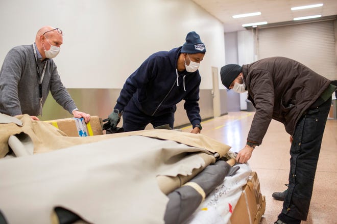 From left, Jim Conner, Ford 3D process director, is helping Nathaniel Crawford II and Jarret Schlaff, co-owners of Pingree Detroit, prepare to transport thousands of dollars in donated leather hides.