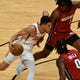 Phoenix Suns guard Devin Booker (1) splits the defense of Miami Heat forward Trevor Ariza (0) and forward Precious Achiuwa (5) during the second half of an NBA basketball game Tuesday, March 23, 2021, in Miami. (AP Photo/Jim Rassol).